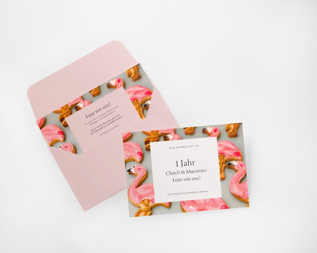 Einladung zum 1-jährigen Jubiläum von Clutch & Macarons mit rosa Flamingo-Keksen, feierlicher Atmosphäre und elegantem Design.